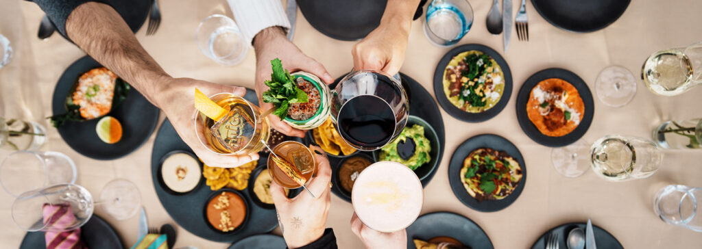 Overhead view of people sharing food and drinks at a dining table